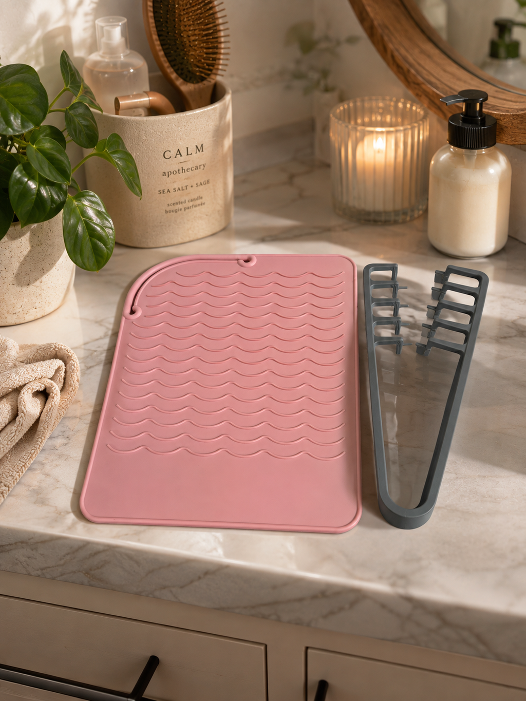 Pink heat resistant silicone mat and grey straightener holder on marble surface